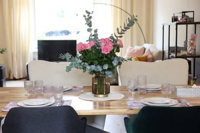 Beautiful table setting with bouquet in dining room. Roses and eucalyptus branches in vase