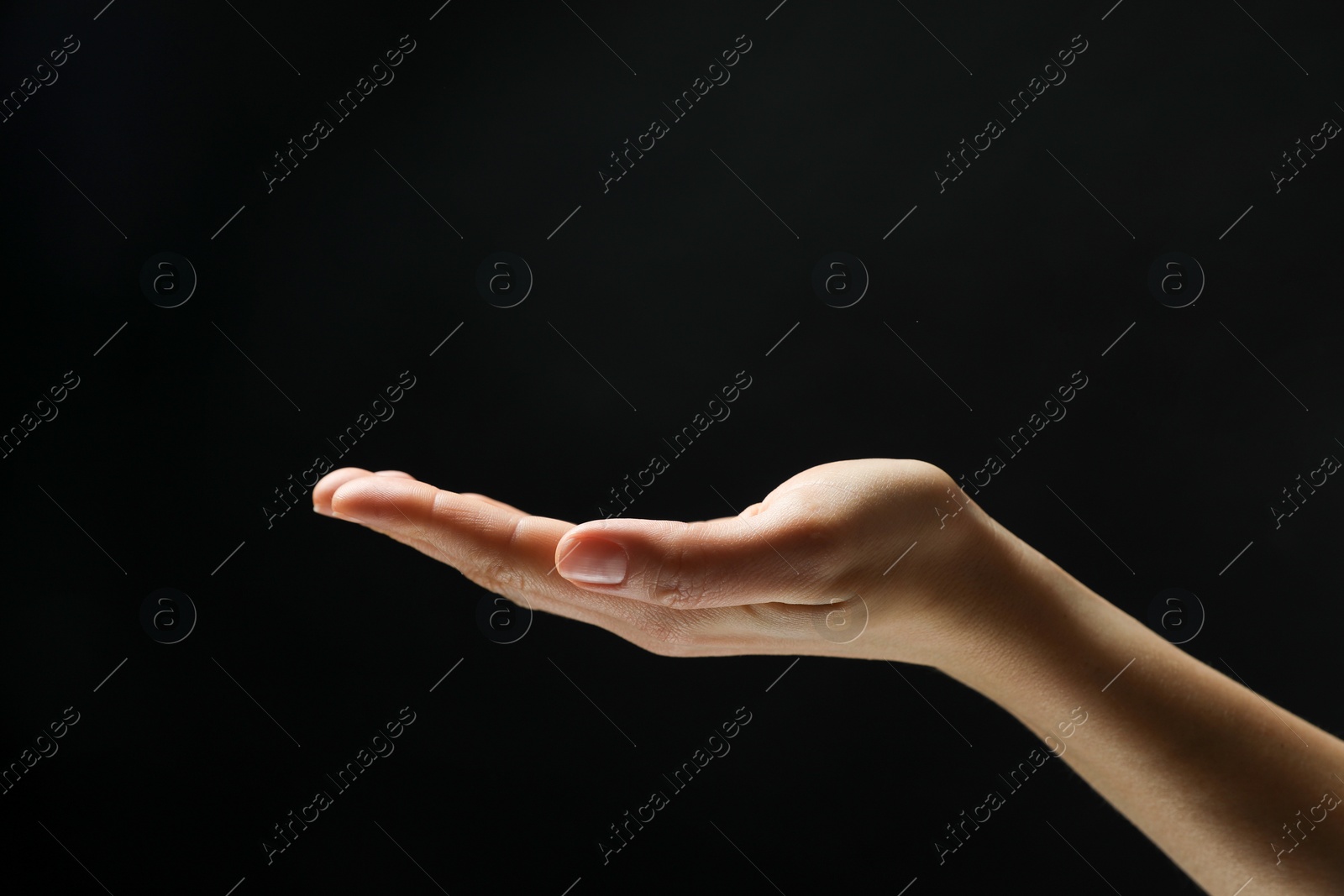 Photo of Woman holding something in hand on black background, closeup. Space for text