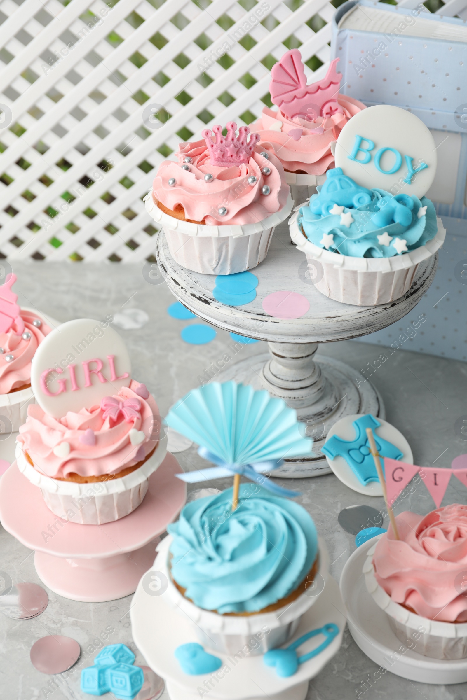 Photo of Delicious cupcakes with light blue and pink cream for baby shower on grey table