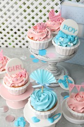 Delicious cupcakes with light blue and pink cream for baby shower on grey table