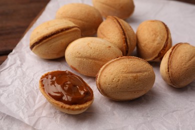 Delicious nut shaped cookies with boiled condensed milk on parchment paper, closeup