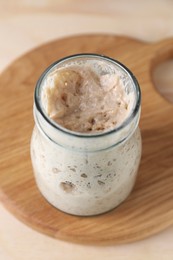Photo of Sourdough starter in glass jar on table, closeup