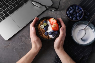 Photo of Woman with tasty granola at workplace, top view