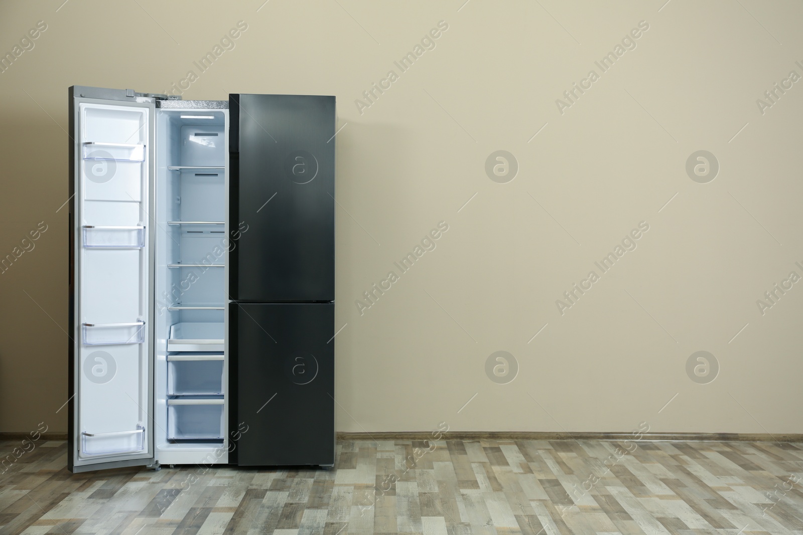 Photo of Modern refrigerator near beige wall, space for text