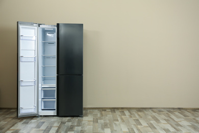 Photo of Modern refrigerator near beige wall, space for text