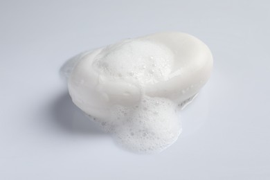 Photo of Soap and fluffy foam on white background