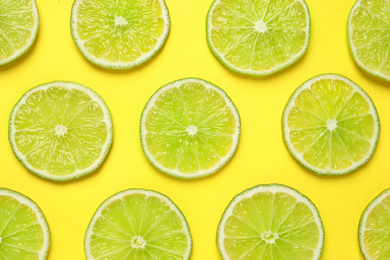 Photo of Fresh juicy lime slices on yellow background, flat lay