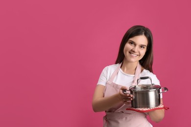 Photo of Happy young woman with cooking pot on pink background. Space for text