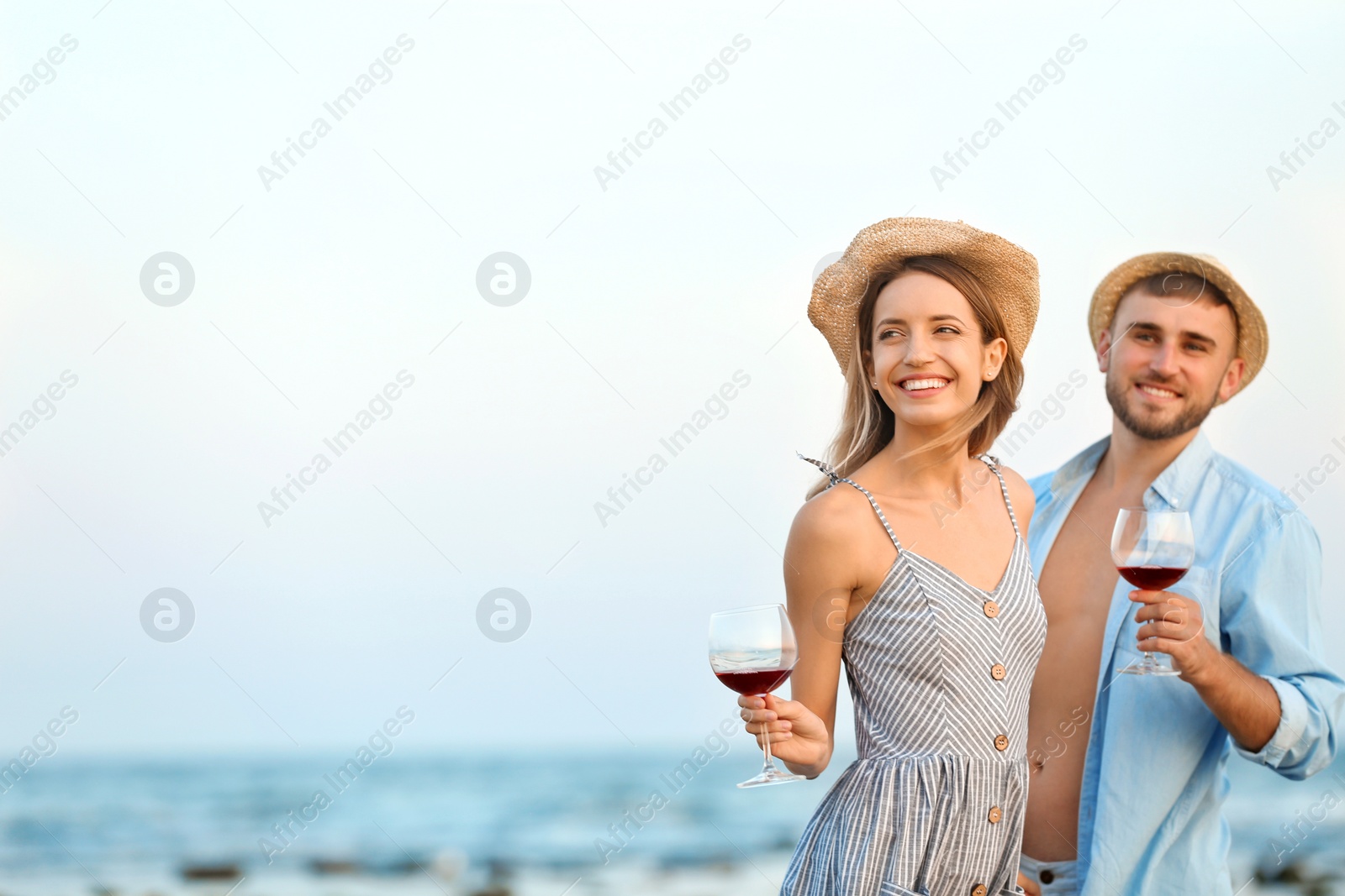 Photo of Young couple with glasses of wine on beach