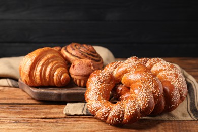 Different tasty freshly baked pastries on wooden table, space for text