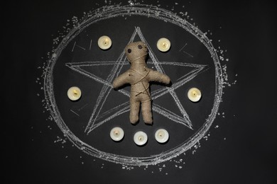 Photo of Voodoo doll pierced with pins and candles in pentagram on table, flat lay