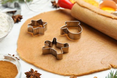 Photo of Dough, cookie cutters and rolling pin on white table. Christmas biscuits