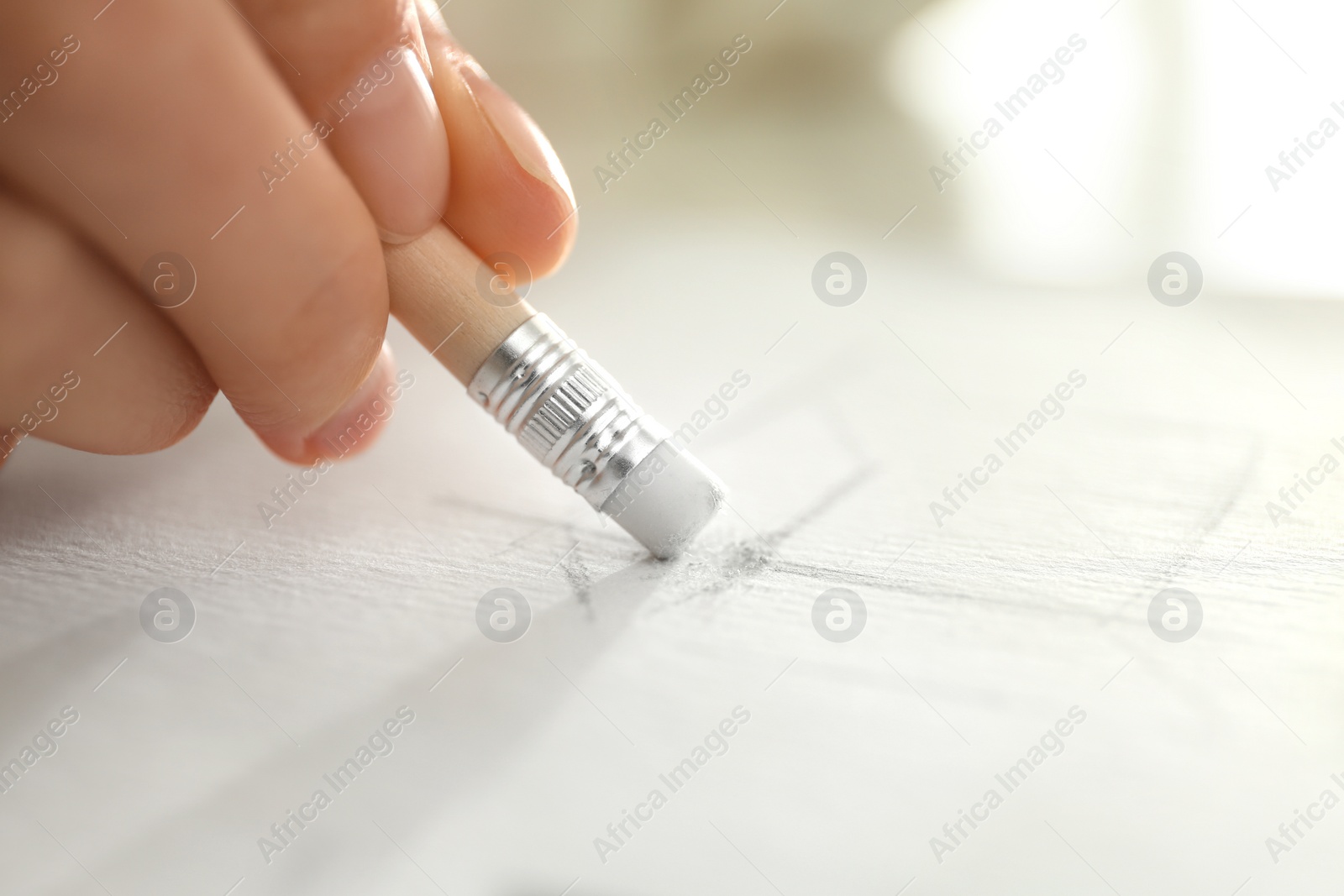 Photo of Woman correcting picture on paper with pencil eraser, closeup