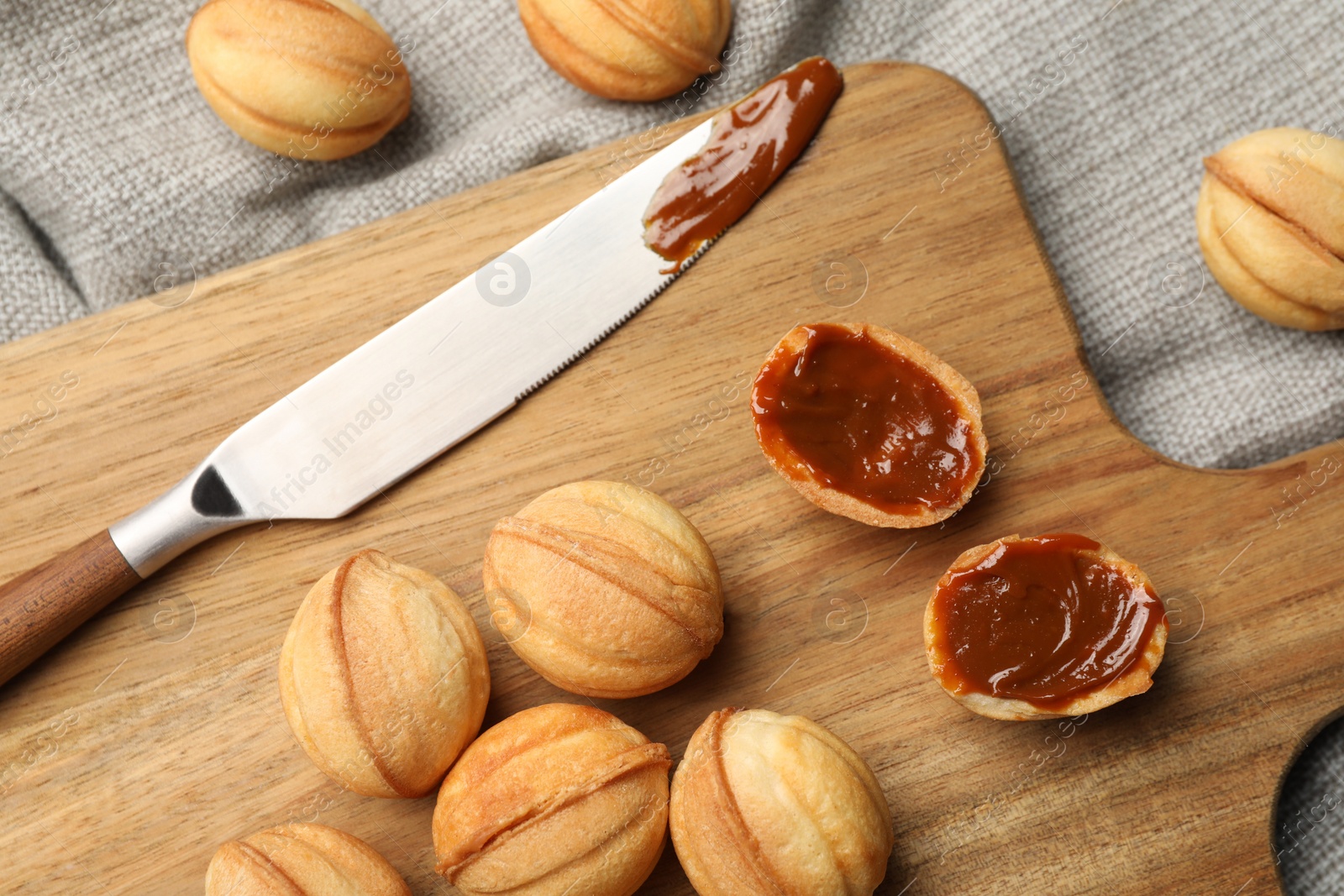 Photo of Homemade walnut shaped cookies with boiled condensed milk on grey tablecloth, flat lay