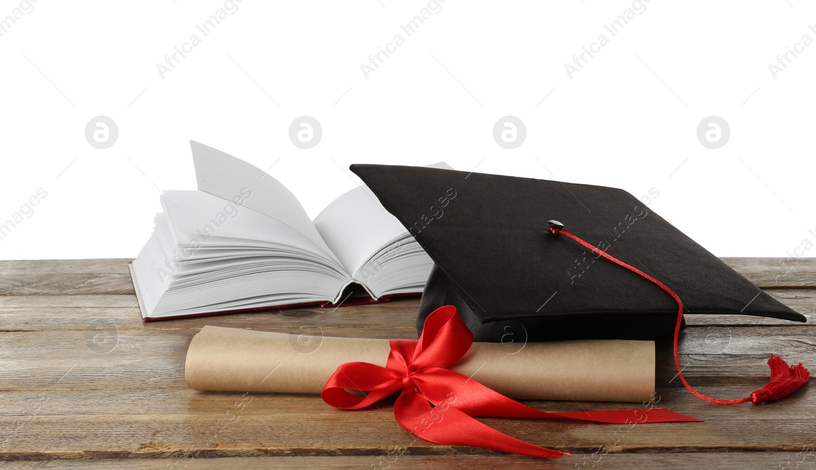 Photo of Graduation hat, book and diploma on wooden table against white background