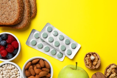Photo of Food and blisters with prebiotic pills on yellow background, flat lay. Space for text