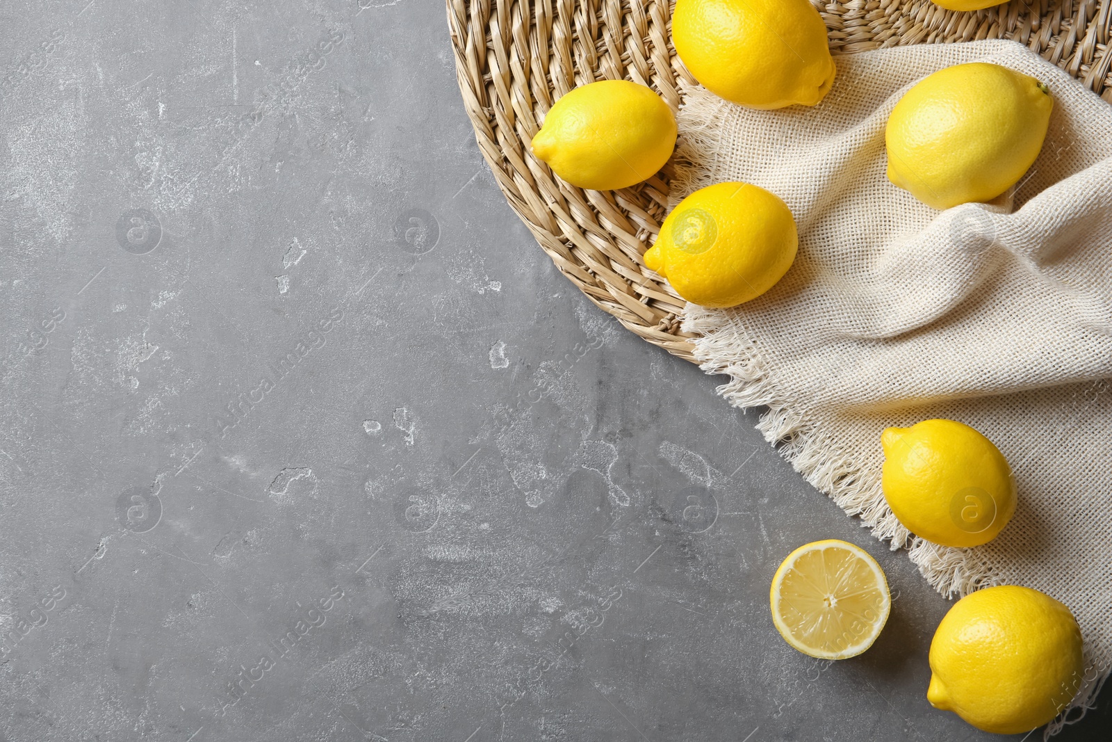 Photo of Flat lay composition with lemons, fabric and straw mat on gray background