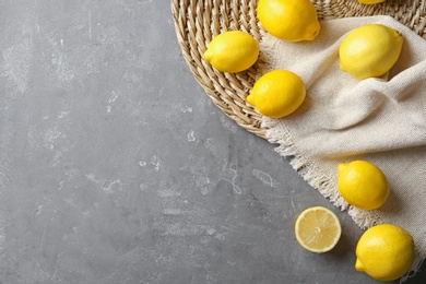 Flat lay composition with lemons, fabric and straw mat on gray background