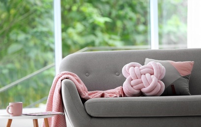 Pillows and plaid on sofa in living room interior. Unusual cushion design