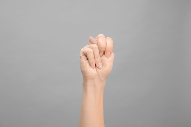 Photo of Woman showing N letter on grey background, closeup. Sign language