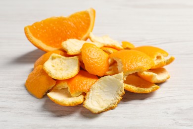 Photo of Orange peels preparing for drying and piece of fresh fruit on white wooden table, closeup