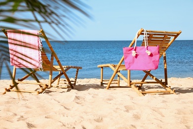 Empty wooden sunbeds and beach accessories on sandy shore