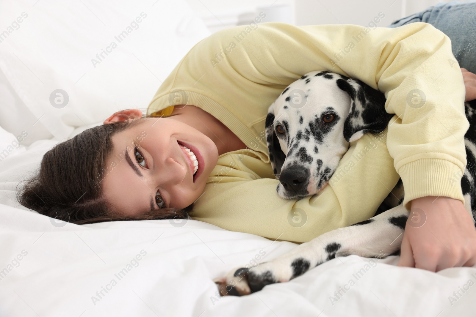 Photo of Beautiful woman with her adorable Dalmatian dog on bed at home. Lovely pet