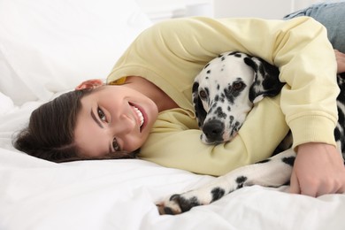 Photo of Beautiful woman with her adorable Dalmatian dog on bed at home. Lovely pet