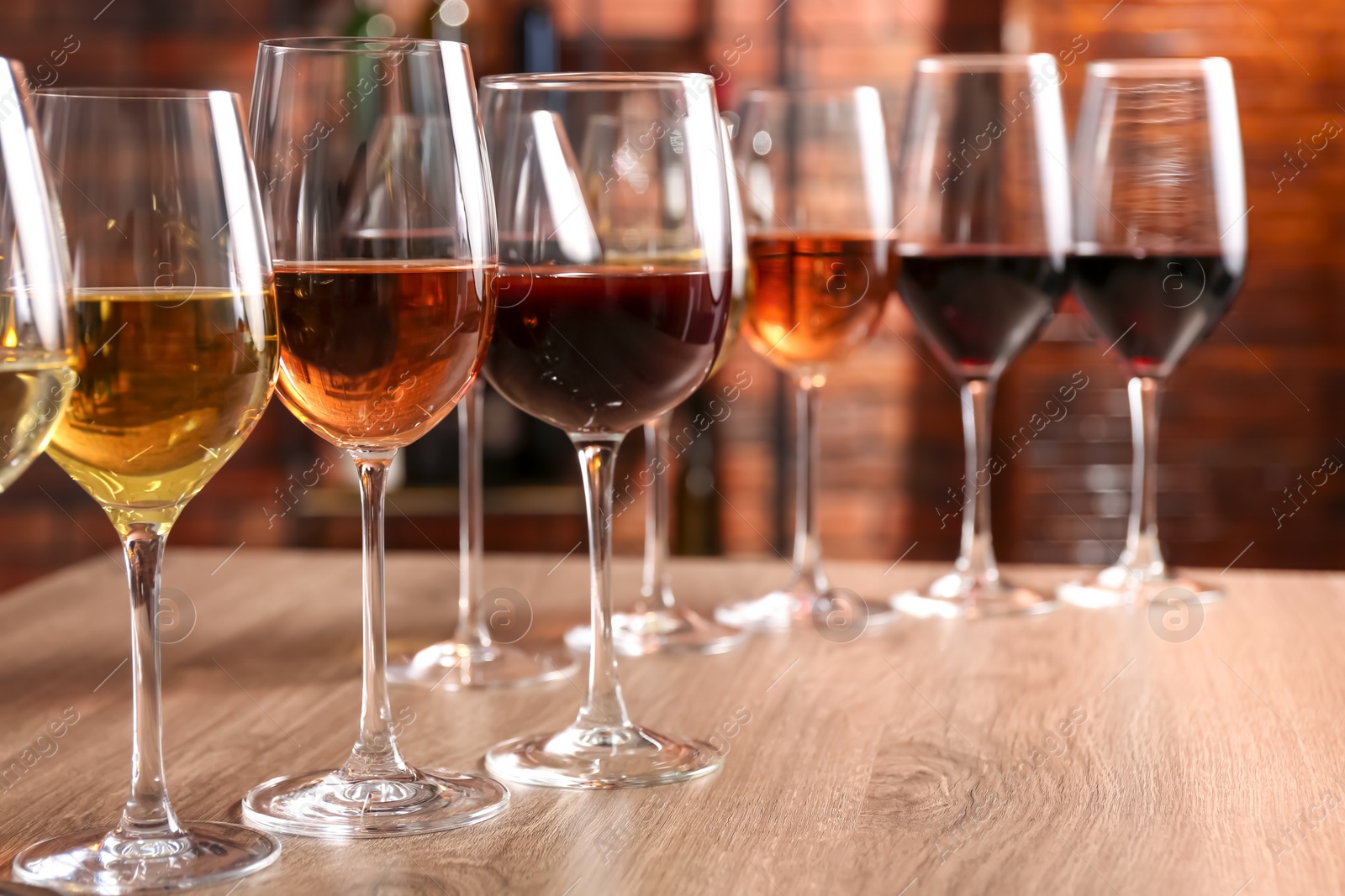 Photo of Different tasty wines in glasses on wooden table, space for text