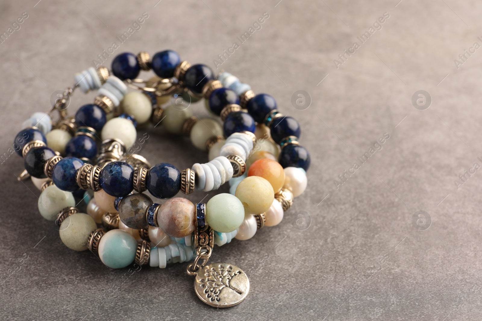 Photo of Beautiful bracelets with gemstones on grey background, closeup. Space for text