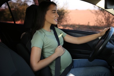 Photo of Young pregnant woman with safety belt in car