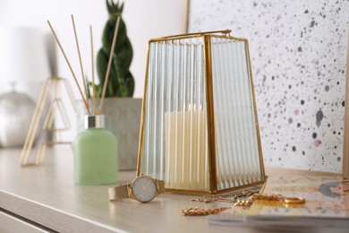 Photo of Beautiful holder with burning candle and stylish accessories on table indoors