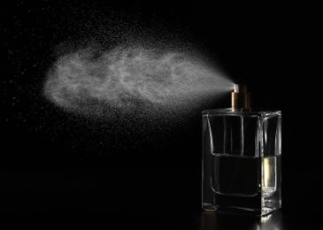 Photo of Woman spraying luxury perfume on black background, closeup. Space for text