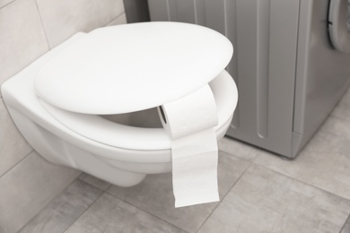 Photo of Toilet bowl with paper roll in bathroom