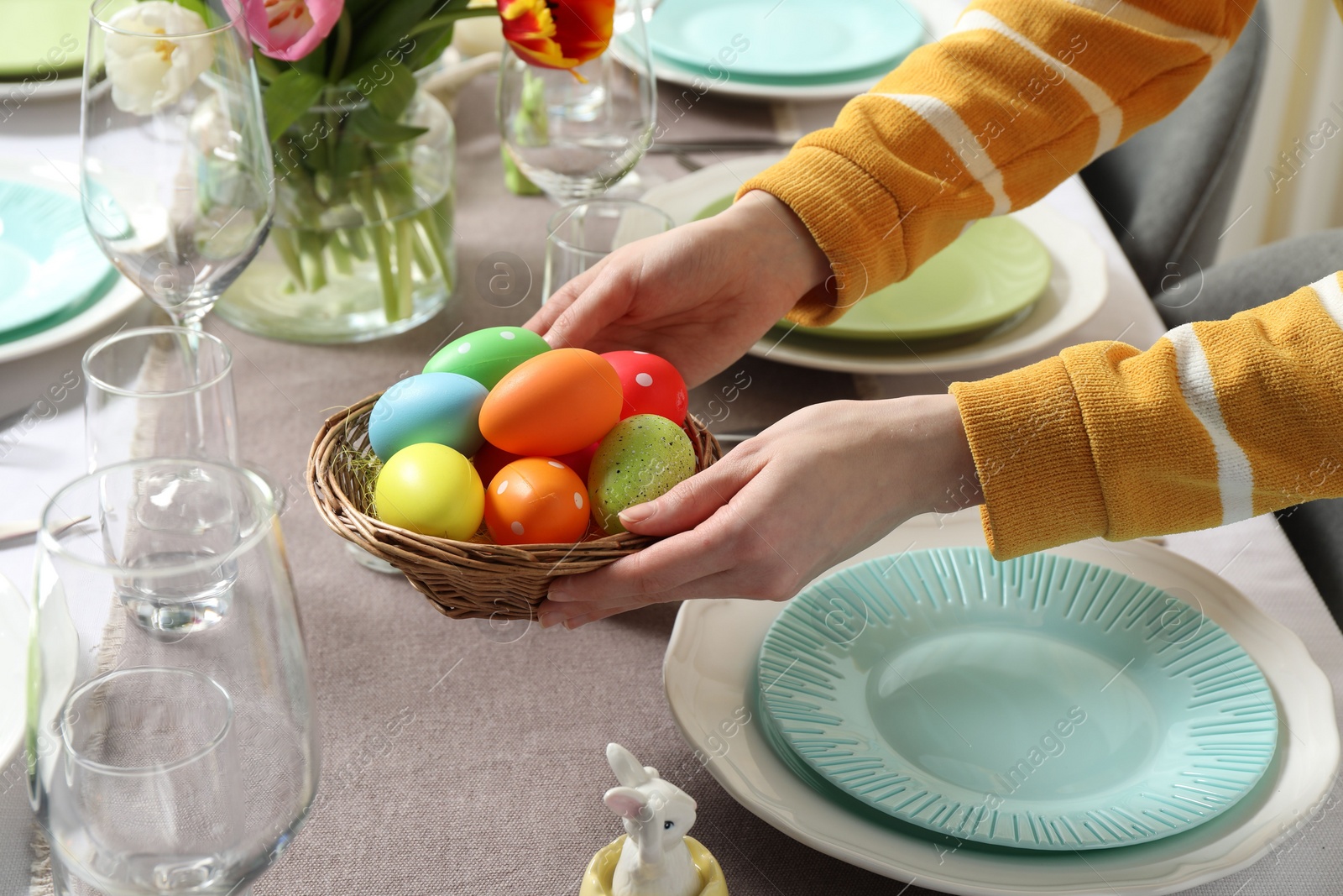 Photo of Woman setting table for festive Easter dinner at home, closeup