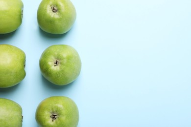 Photo of Ripe green apples on light blue background, flat lay. Space for text