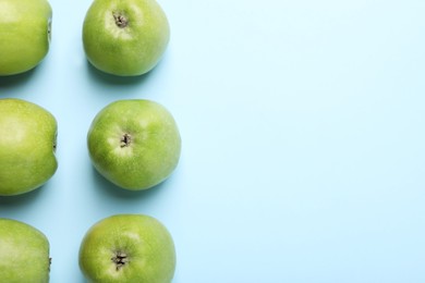 Ripe green apples on light blue background, flat lay. Space for text