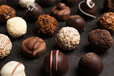 Photo of Different delicious chocolate candies on black table, closeup