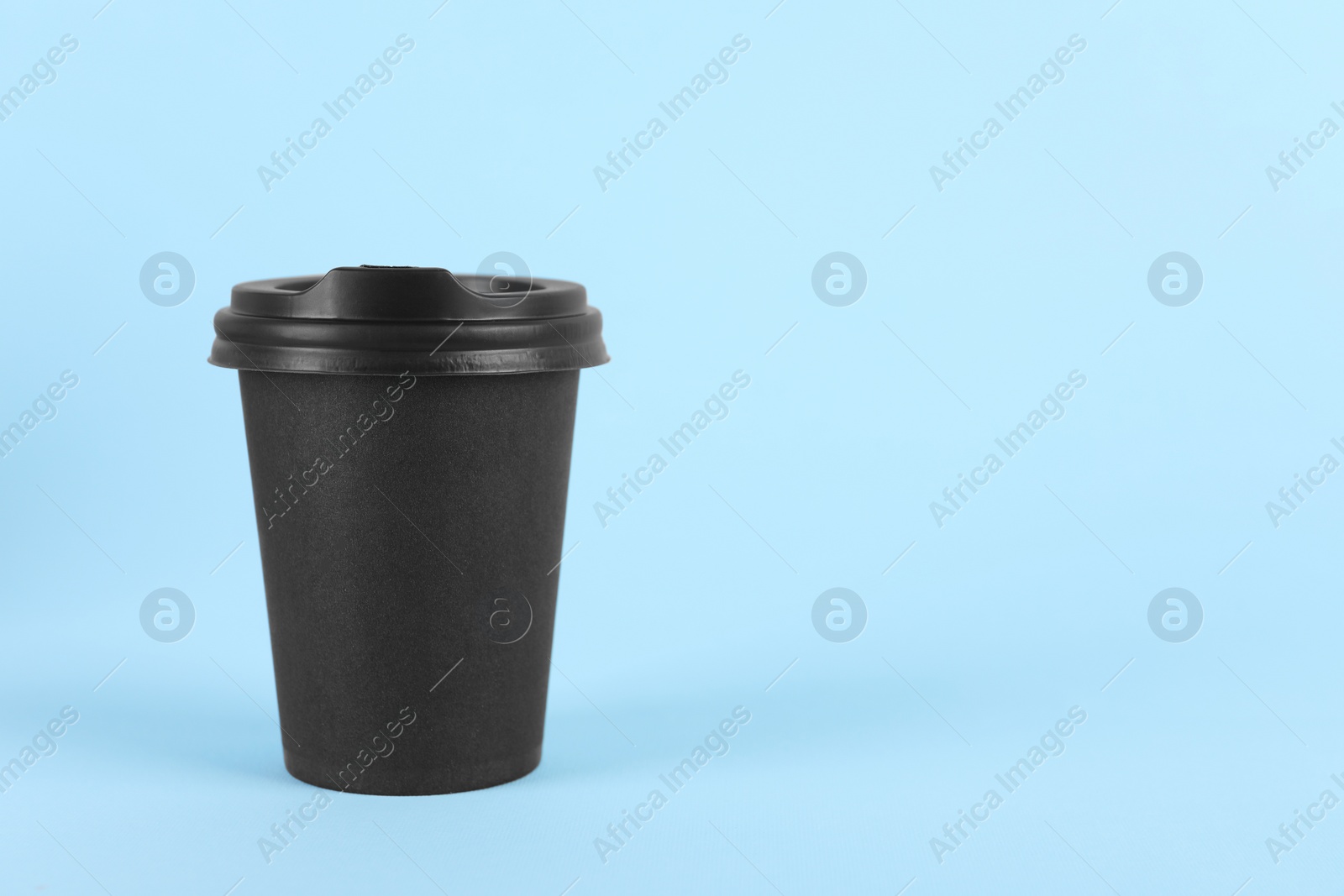 Photo of Black paper cup with plastic lid on light blue background, space for text. Coffee to go