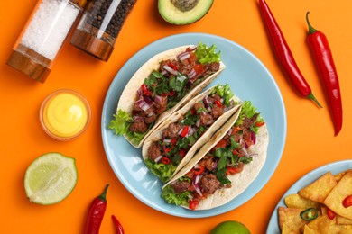 Photo of Flat lay composition with delicious tacos on orange table