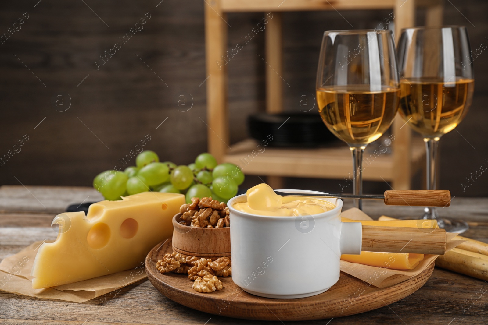 Photo of Pot of tasty cheese fondue and products on wooden table