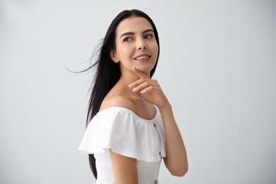 Beautiful young woman on light grey background