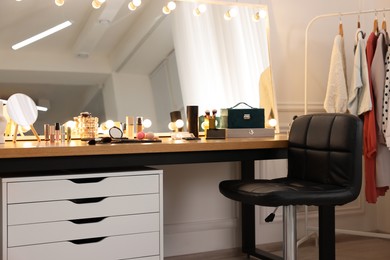 Makeup room. Stylish dressing table with mirror, chair and clothes rack