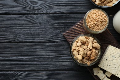 Photo of Different natural soy products on black wooden table, flat lay. Space for text