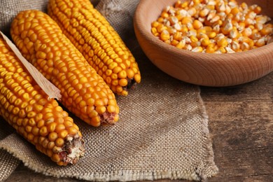 Delicious ripe corn cobs and bowl with seeds on wooden table