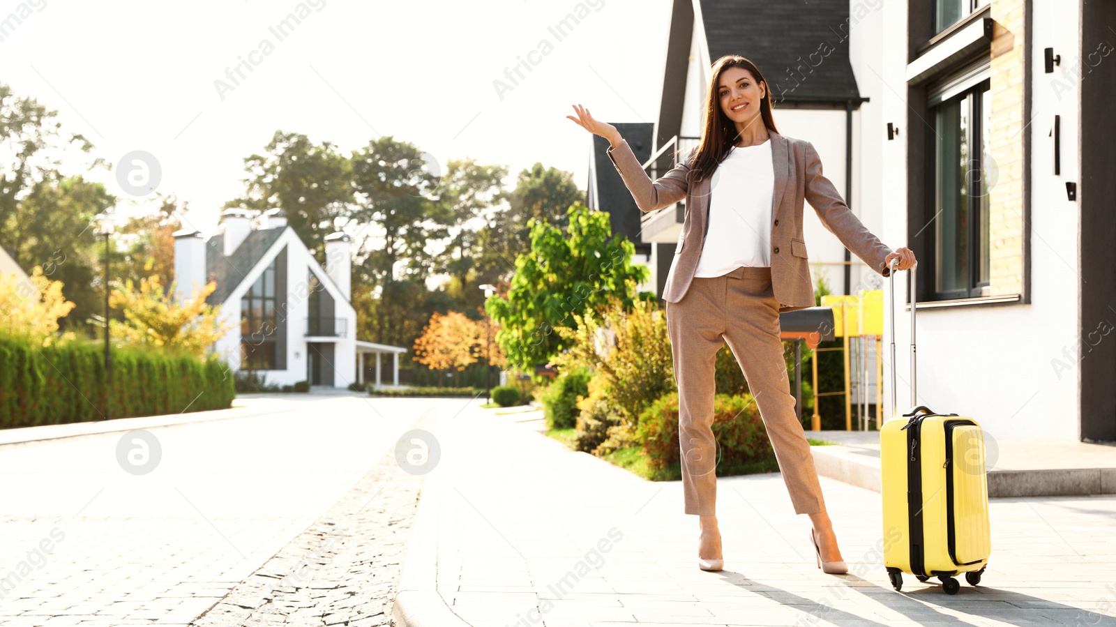 Photo of Young businesswoman with suitcase outdoors. Moving day