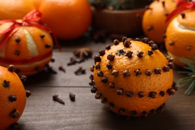 Pomander balls made of tangerines with cloves on wooden table, closeup