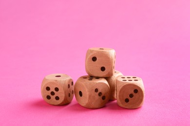 Photo of Many wooden game dices on pink background, closeup