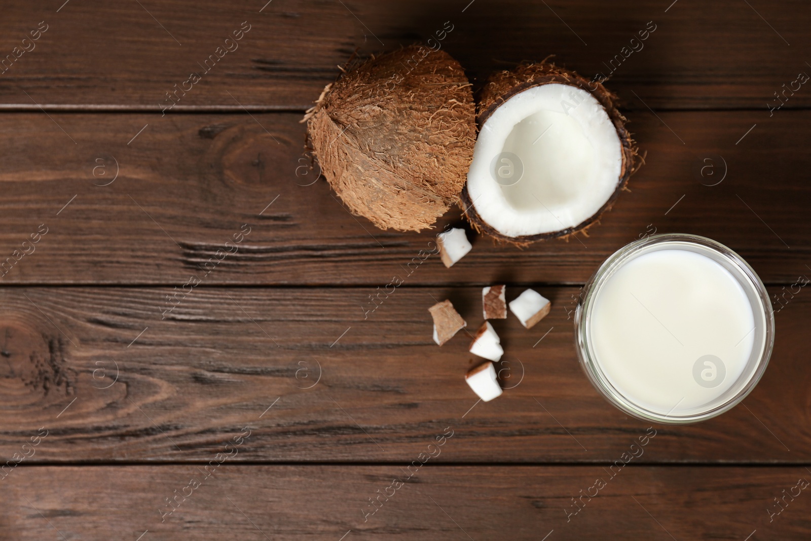 Photo of Glass of coconut milk and fresh nuts on wooden background, top view