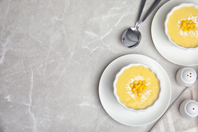 Photo of Delicious corn cream soup served on grey marble table, flat lay. Space for text